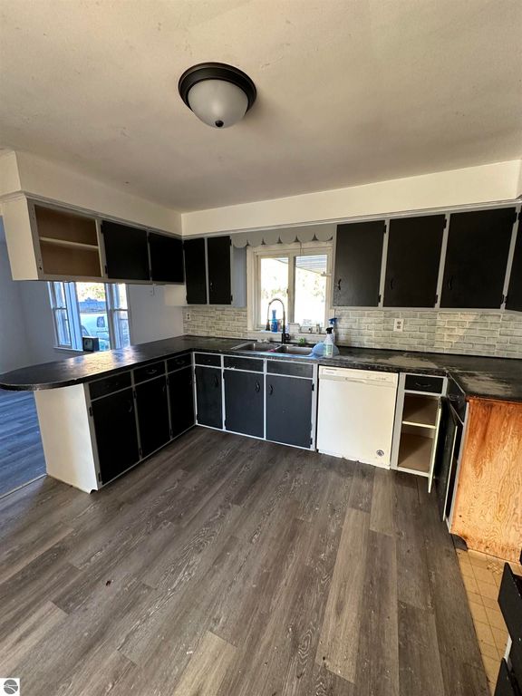 Kitchen interior featuring black cabinets, a sink, and a window, with a view of the outdoors, in a home for sale at 4419 10 Mile Road, Evart, MI.
