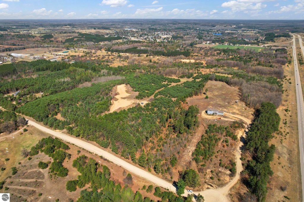 Aerial view of 7.62-acre parcel of land in Manton, MI, featuring wooded areas and open space, ideal for outdoor activities and privacy, with nearby road access and proximity to downtown.