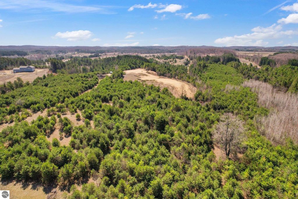 Aerial view of 7.62-acre wooded parcel in Manton, MI, featuring dense greenery, open land, and scenic landscape ideal for outdoor activities and privacy.