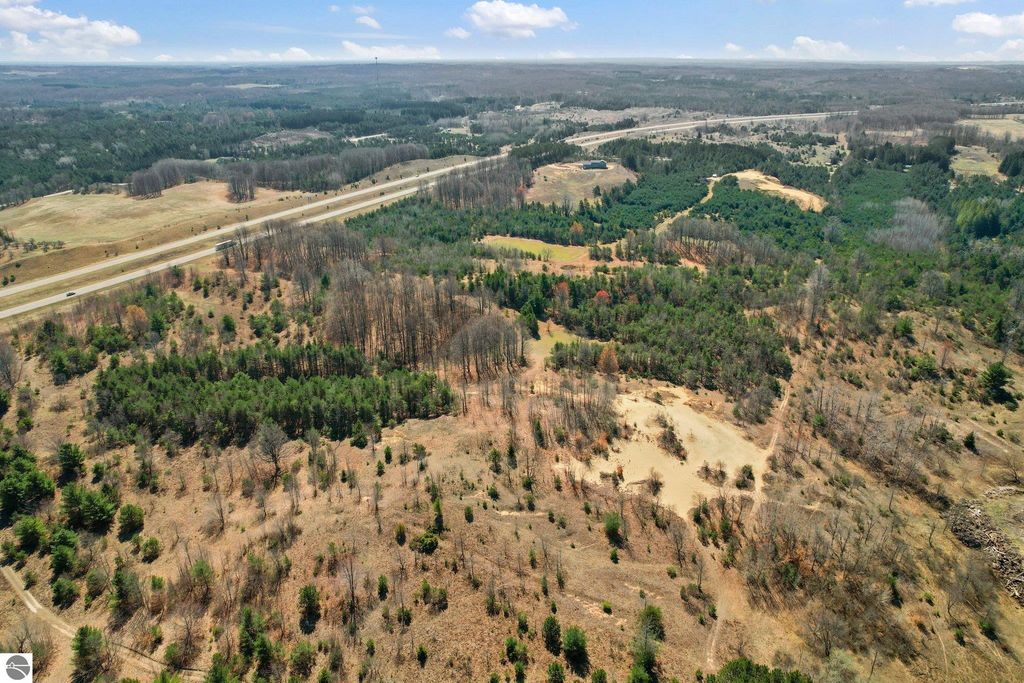 Aerial view of 7.62-acre parcel in Manton, MI, showcasing wooded areas, open land, and proximity to road, ideal for outdoor activities and privacy.