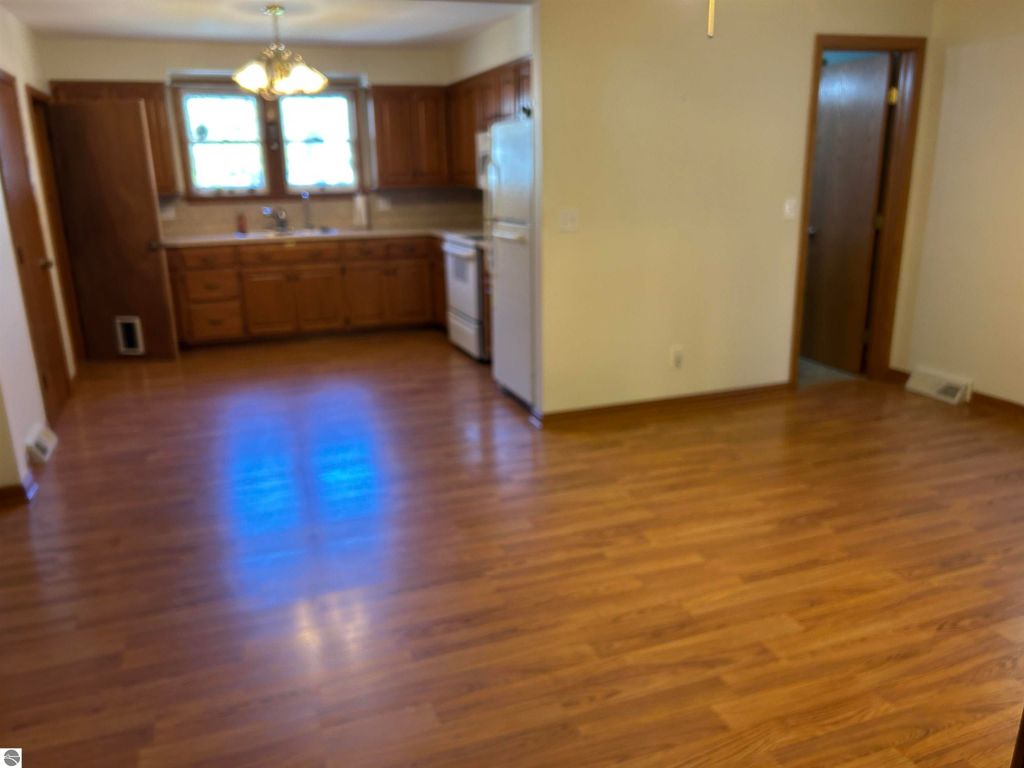 Kitchen interior of 11138 W 2nd Street, Fowler, MI, featuring wooden cabinets, appliances, and hardwood flooring, ideal for family gatherings.