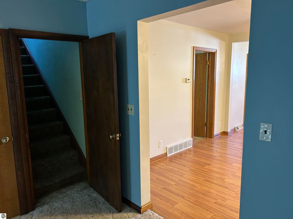 Interior view of a home at 11138 W 2nd Street, Fowler, MI, featuring an open hallway, staircase, and doorways leading to additional rooms, showcasing hardwood flooring and light-colored walls.
