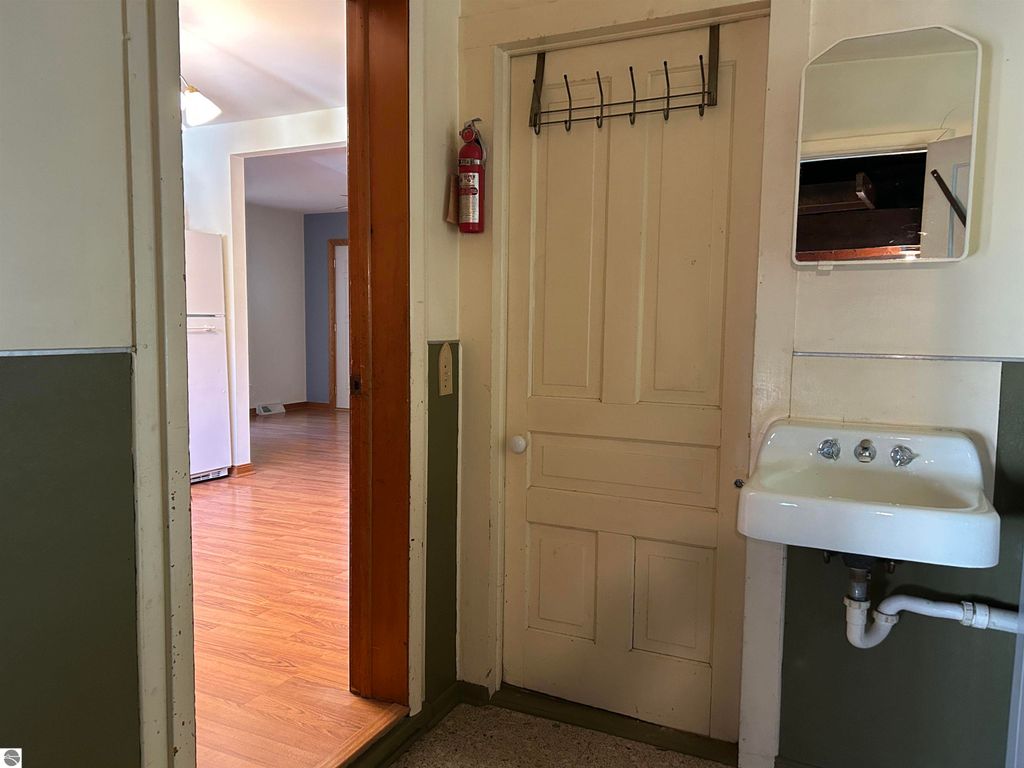 Interior view of a home entryway featuring a coat rack, small sink, and doorway leading to a kitchen, highlighting the property's layout at 11138 W 2nd Street, Fowler, MI.