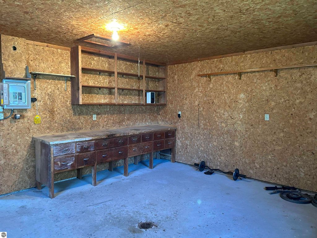 Garage interior with wooden workbench, shelves, and storage space, suitable for a workshop or craft room, located at 11138 W 2nd Street, Fowler, MI.