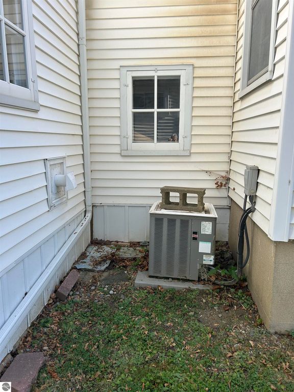 Side view of the home at 11138 W 2nd Street, Fowler, MI, showing an air conditioning unit, window, and exterior siding details.