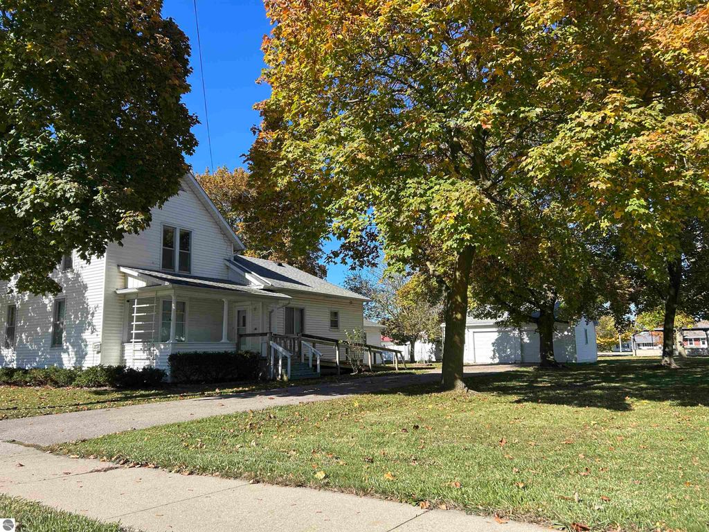 4-bedroom home at 11138 W 2nd Street, Fowler, MI, featuring a spacious yard with mature trees, visible detached garage, and inviting front porch.
