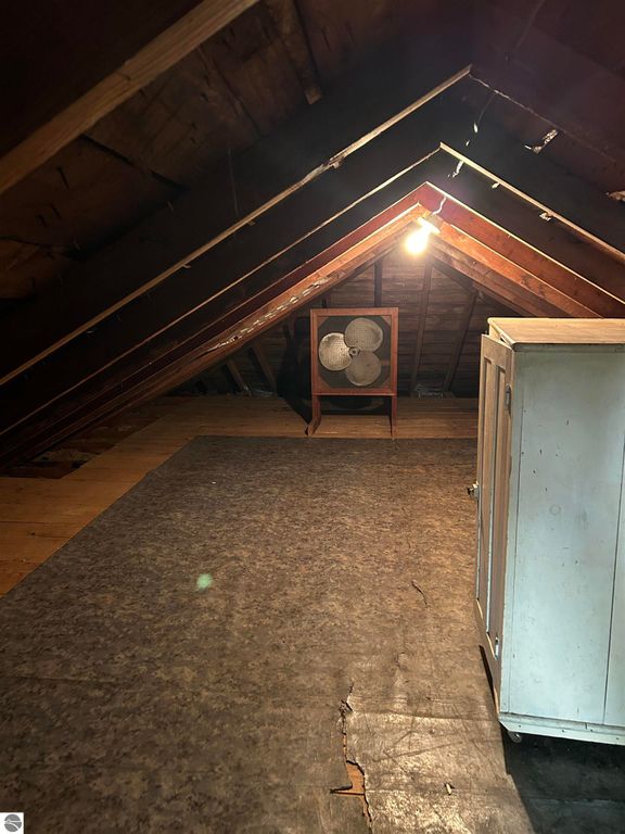 Attic space with sloped wooden ceiling, vintage fan, and white storage cabinet, suitable for conversion into an art studio or playroom, as mentioned in the Fowler real estate listing.