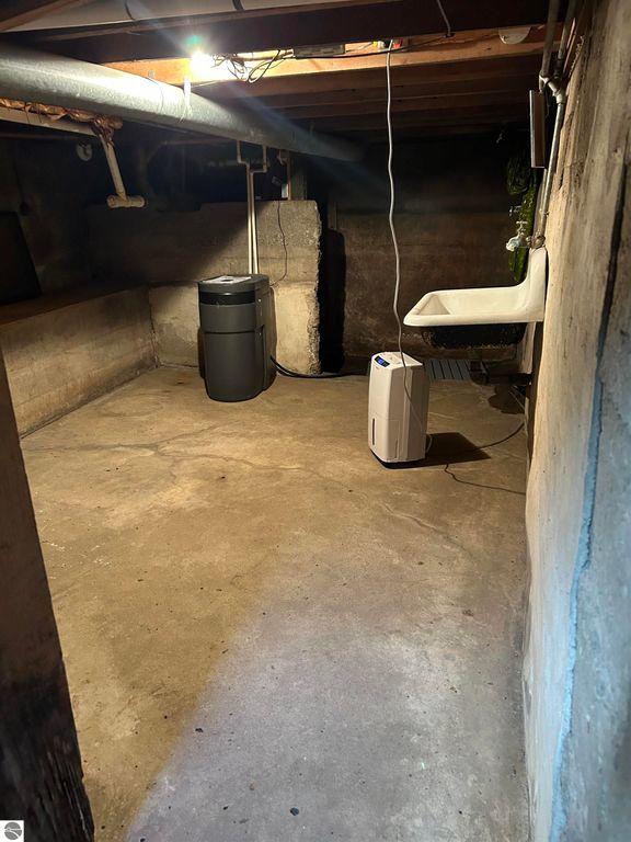 Basement space of a home featuring a dehumidifier, utility sink, and concrete flooring, suitable for storage or potential renovation, relevant to the property listing at 11138 W 2nd Street, Fowler, MI.