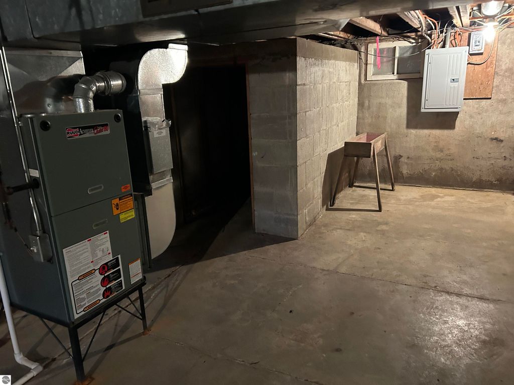 Basement interior with a furnace, concrete walls, and a workbench, showcasing the utility space of the 4-bedroom home at 11138 W 2nd Street, Fowler, MI.