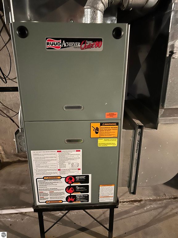 Ruud Achiever gas furnace model 80, featuring safety warnings and operational instructions, located in the basement of a home for sale at 11138 W 2nd Street, Fowler, MI.