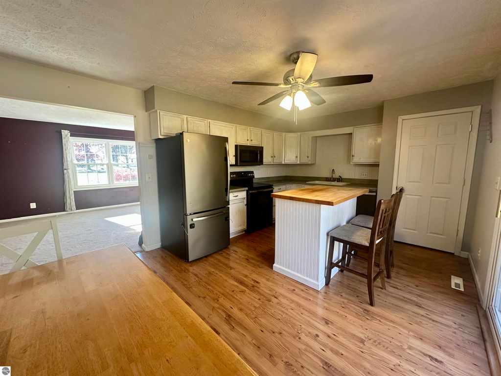 Modern bi-level kitchen with stainless steel appliances, wooden island, and spacious dining area, showcasing a welcoming atmosphere in the Lake City home listing.