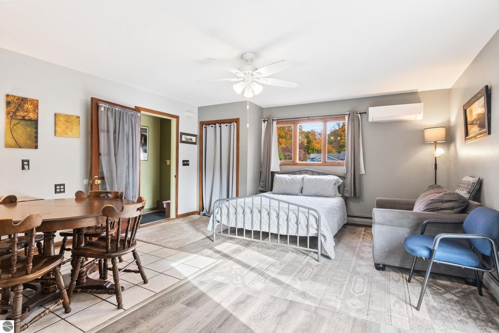 Cozy interior of a self-contained apartment featuring a dining table, bed, and seating area, showcasing modern updates in a Victorian-style home in Onekama, MI.