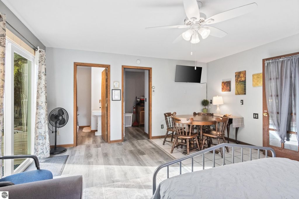Interior view of a cozy, furnished bedroom with a dining area, featuring a round wooden table, ceiling fan, and modern decor, highlighting the inviting atmosphere of the Victorian home in Onekama, MI.