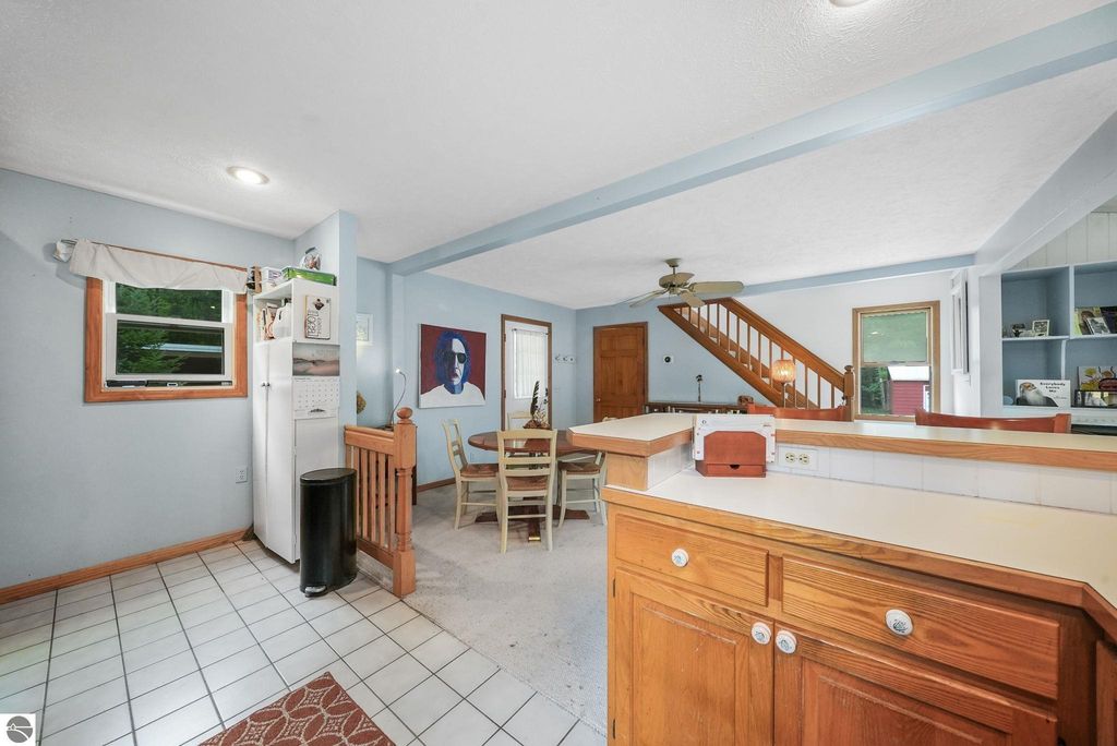 Interior view of farmhouse kitchen and dining area at 5361 N Manitou Trail, featuring white appliances, wooden accents, and a staircase leading to the upper level.