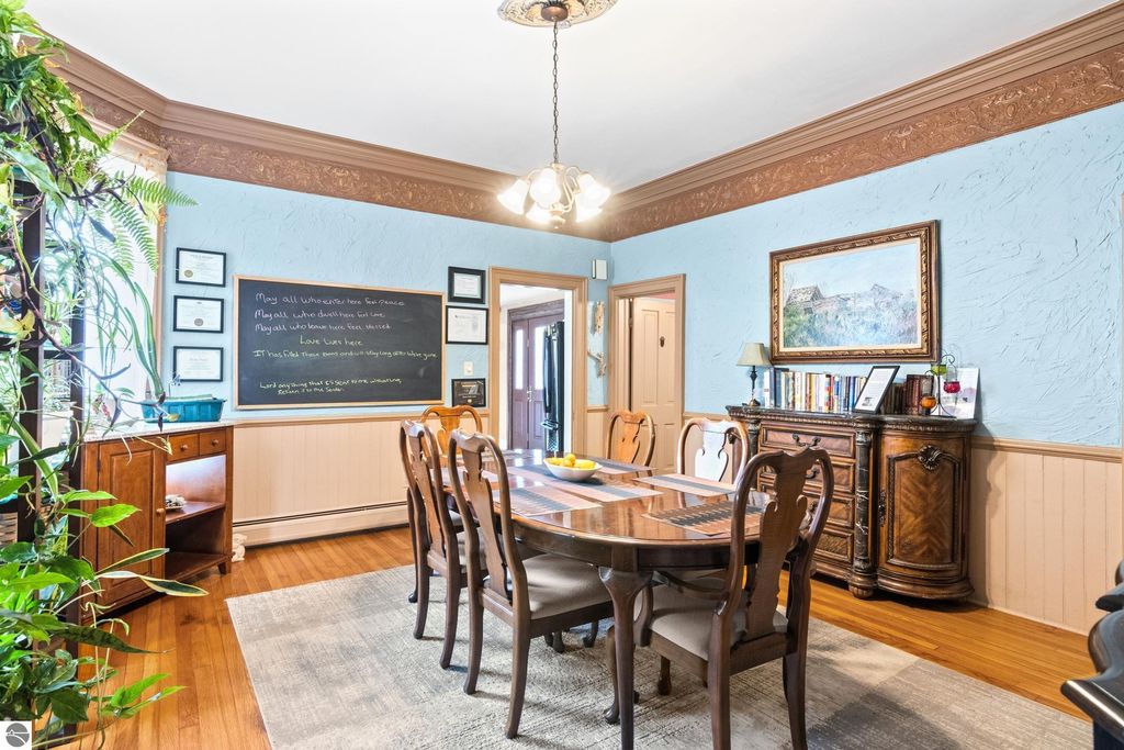 Victorian dining room featuring a wooden dining table, elegant chairs, decorative wall molding, and a blue accent wall, showcasing original wood trim and modern updates, ideal for a bed and breakfast setting.