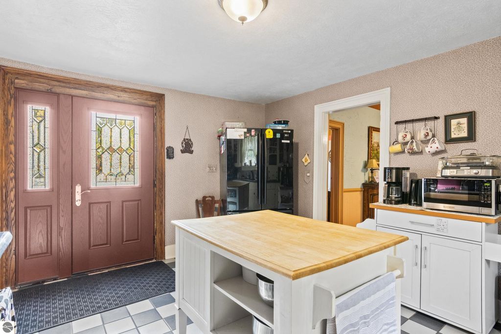 Victorian-style kitchen entrance featuring double doors with stained glass, wooden cabinetry, and modern appliances, showcasing a blend of historic charm and contemporary updates in a Onekama home.