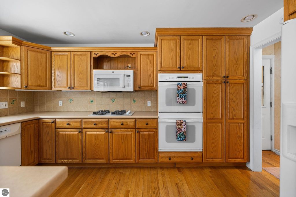 Inviting kitchen space in Traverse City ranch home featuring hardwood floors, large windows, oak cabinetry, and modern appliances, ideal for family gatherings and daily living.
