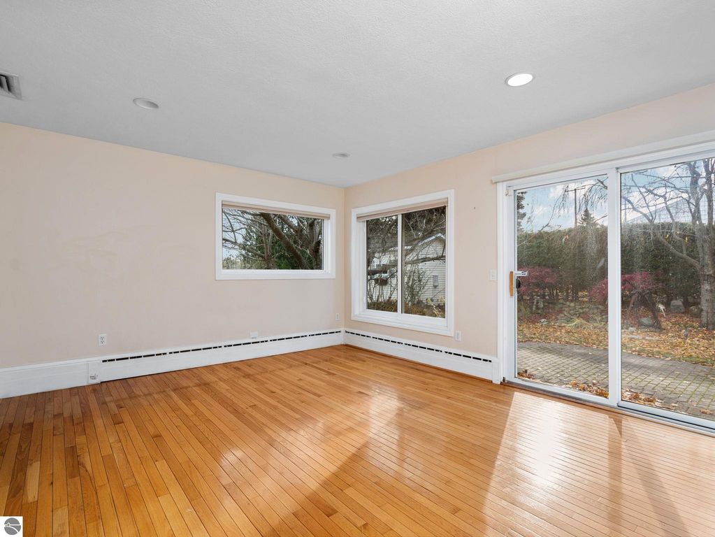Spacious sunlit living area with hardwood floors and sliding glass door leading to the backyard at 109 Boughey Street, Traverse City, MI.