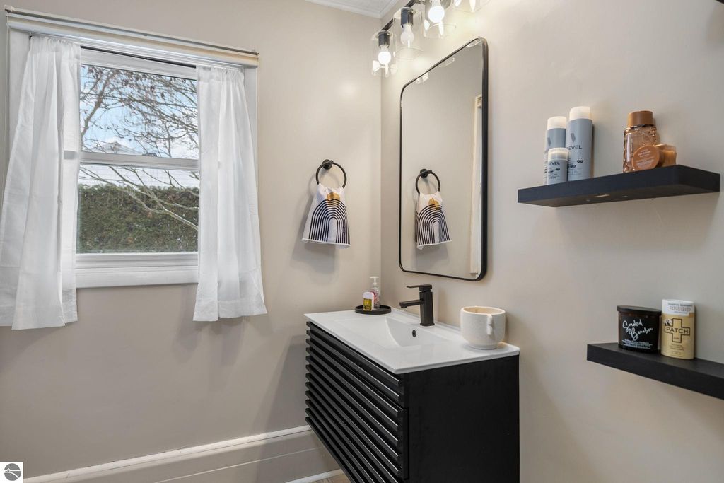 Bright and spacious room with hardwood flooring, large windows providing natural light, and clean white walls, showcasing a welcoming atmosphere in a Traverse City home.