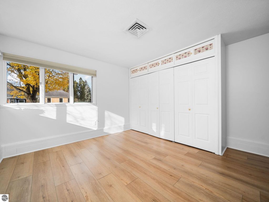 Interior view of a room in a Traverse City ranch home featuring hardwood flooring, a doorway leading to a bathroom, and a closet, emphasizing the updated living space.