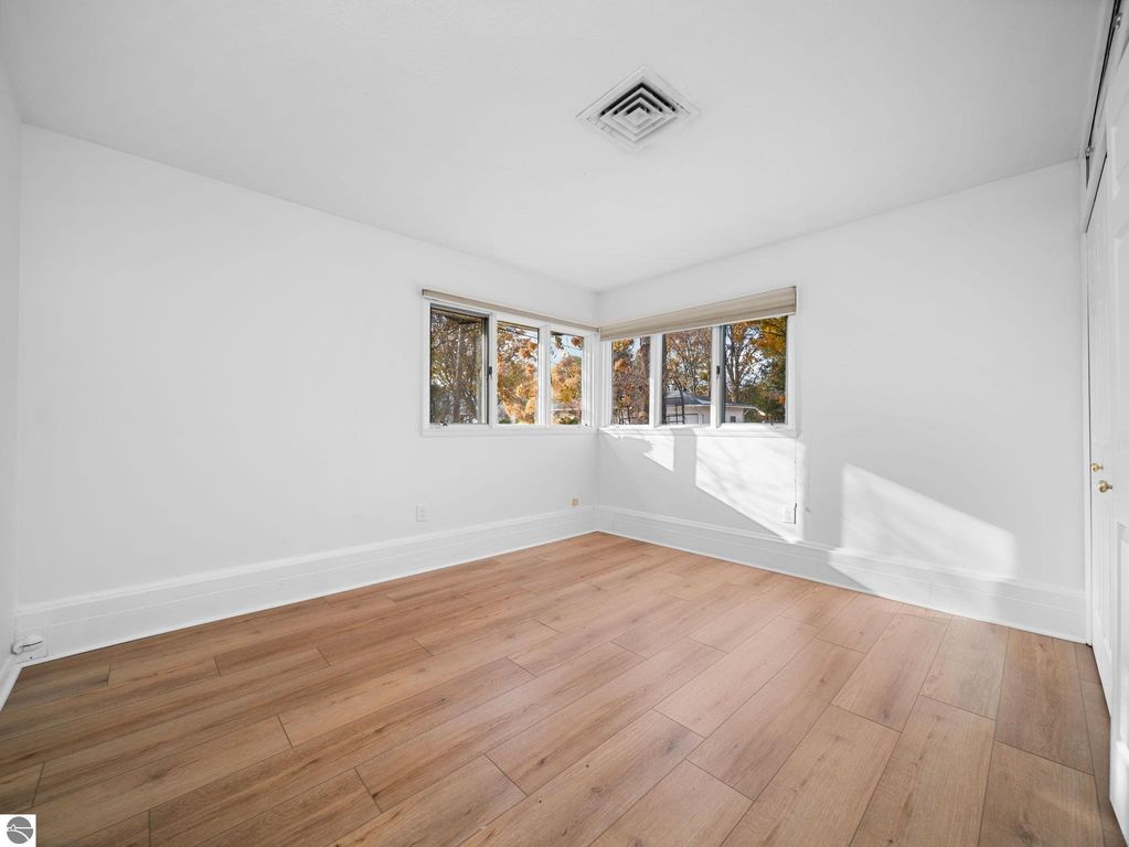 Basement family room with carpeted flooring, staircase leading to upper level, and a doorway to a bathroom featuring a vanity and mirror.