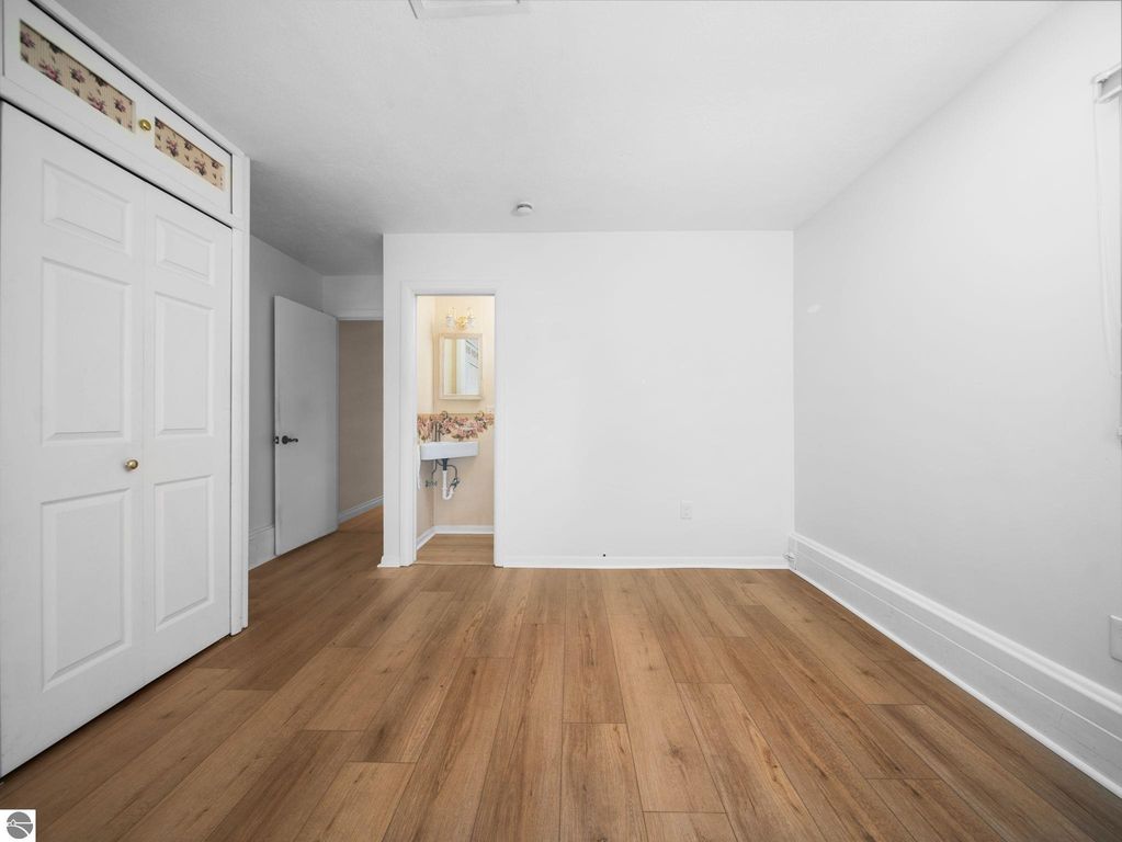 Bathroom interior featuring a double sink vanity with wooden cabinetry, decorative lighting, and a colorful floral shower curtain, complemented by a pink and white checkered rug.