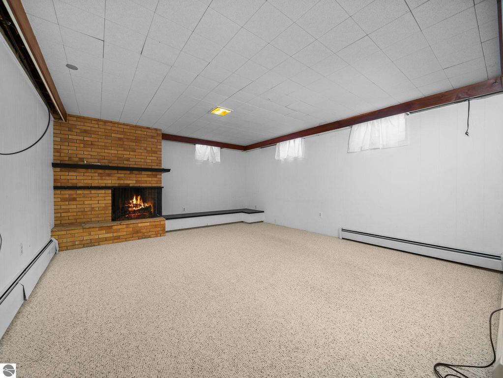 Spacious finished basement area with decorative floral wall panels, cozy lighting fixture, and neutral carpeting, showcasing potential for additional living space in Traverse City ranch home.
