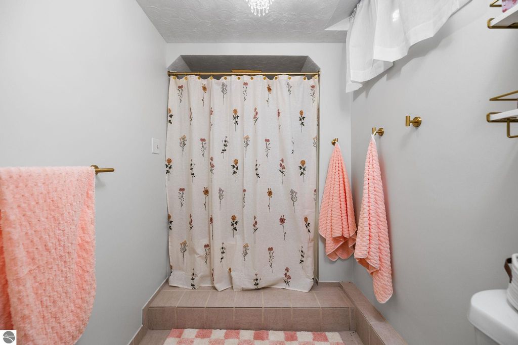 Spacious finished basement area with carpet flooring, track lighting, and closet doors, ideal for a family room or additional living space in a Traverse City ranch home.