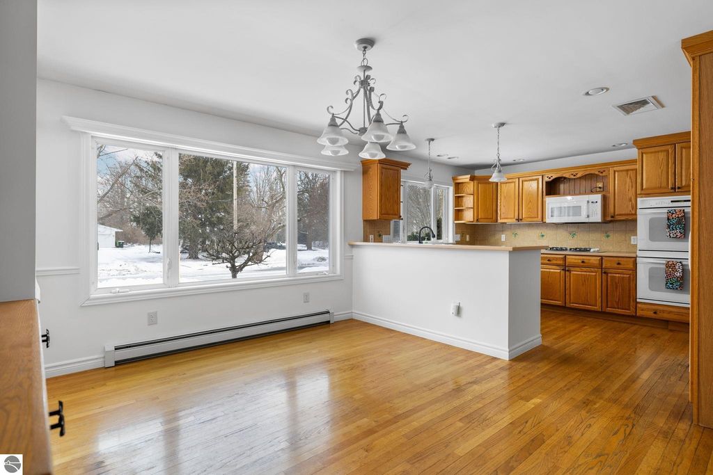 Spacious living room featuring hardwood floors, a cozy fireplace framed by built-in bookcases, and large windows providing natural light, ideal for the Traverse City home at 109 Boughey Street.