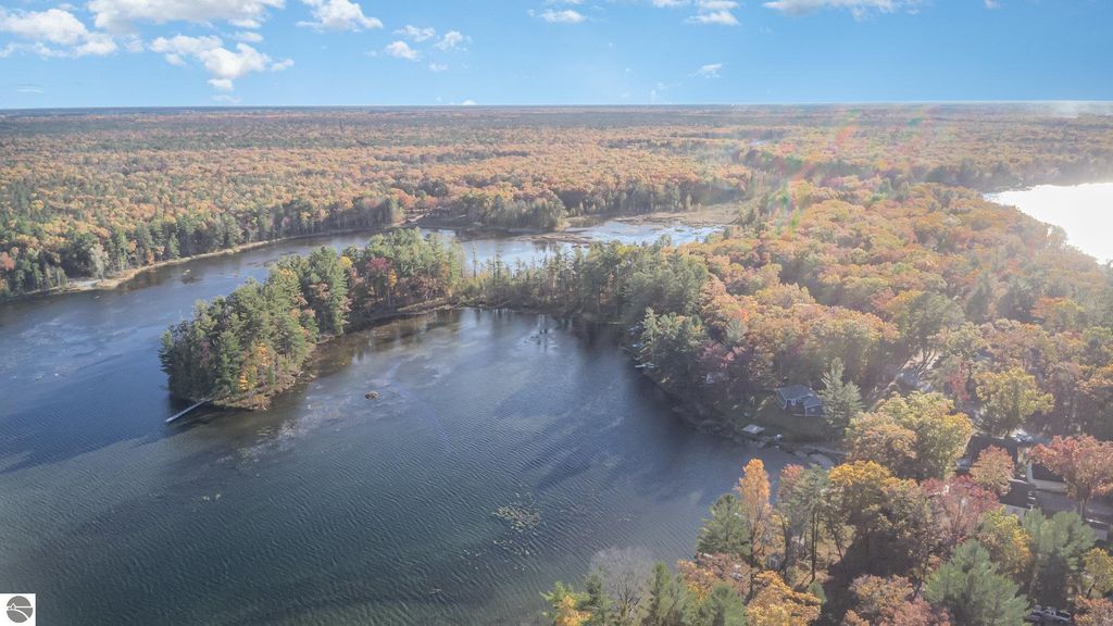 Aerial view of Big Island Lake surrounded by colorful autumn foliage, showcasing lush greenery and water features near 2096 Timber Trail, National City, MI.