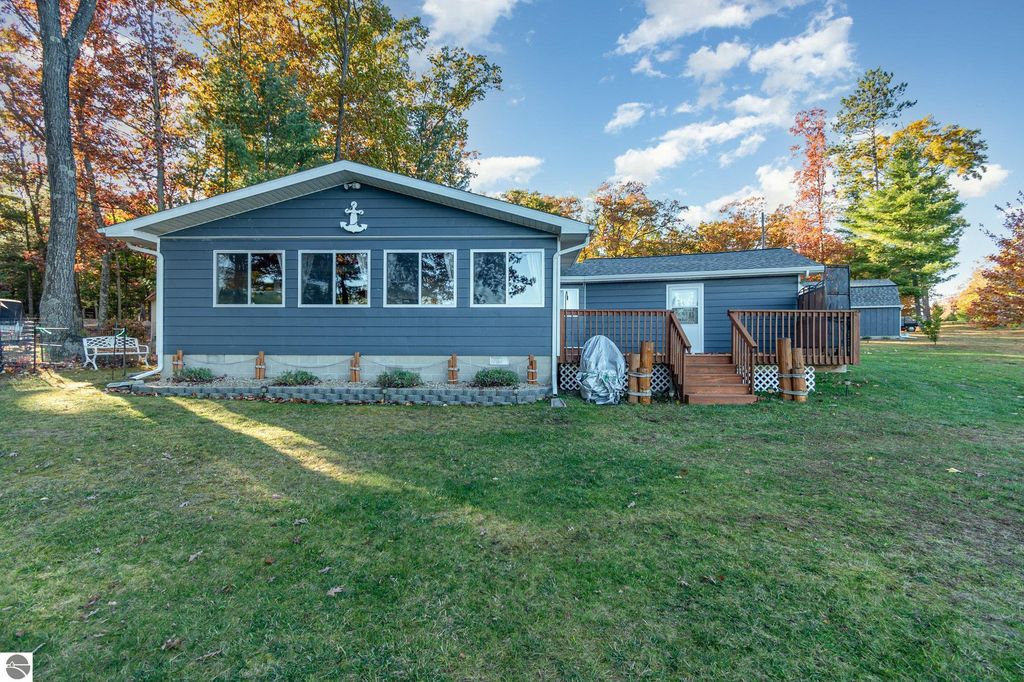 Beautifully remodeled knotty-pine home on Big Island Lake, featuring large windows, spacious deck, and landscaped yard.