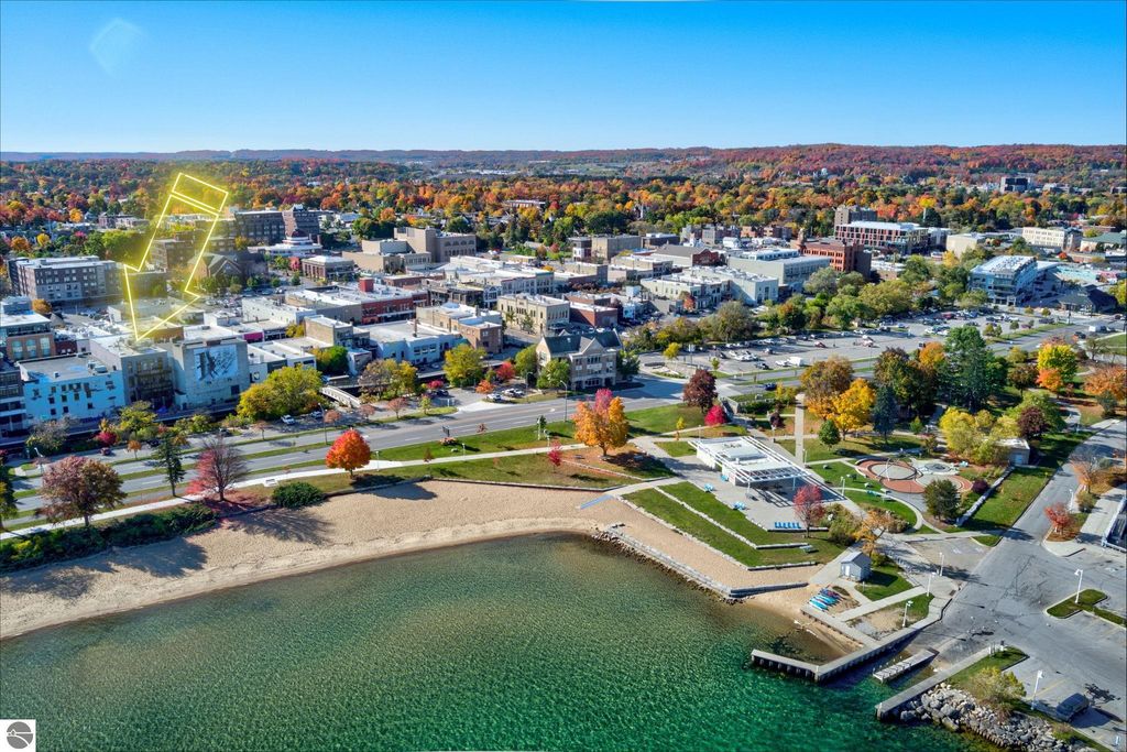 Aerial view of downtown Traverse City, Michigan, highlighting 237 E Front Street with colorful fall foliage, waterfront, and nearby parks.
