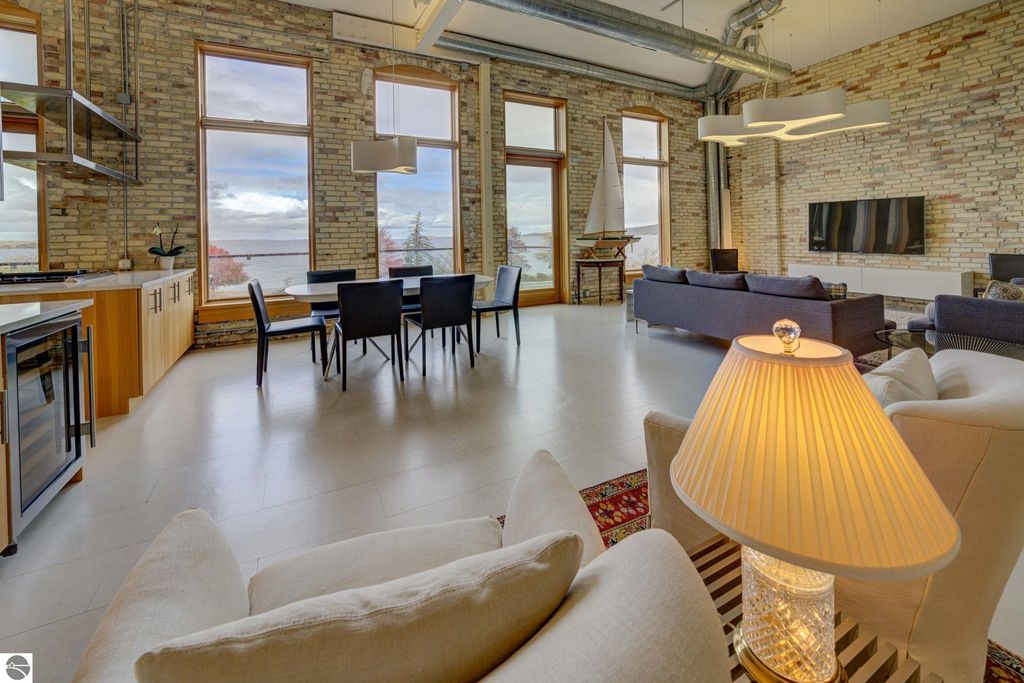 Modern downtown condo interior with large windows showcasing bay views, contemporary furnishings, and open layout, highlighting the architectural design and natural light.