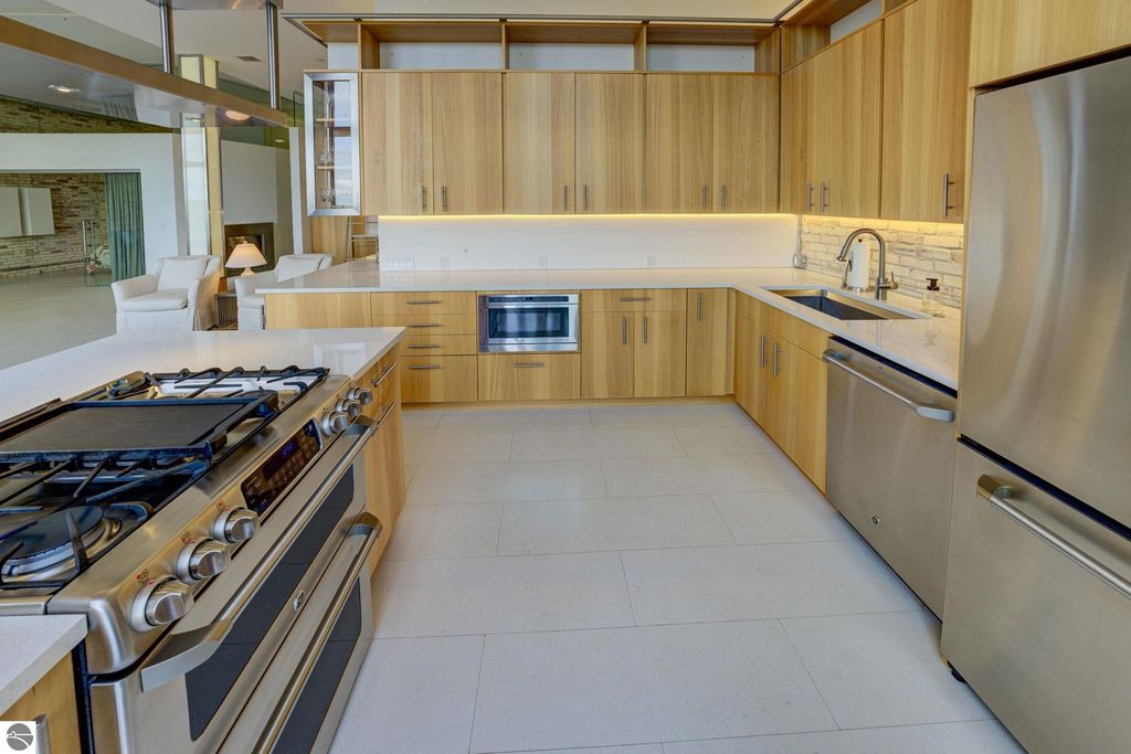 Modern kitchen with wooden cabinetry, stainless steel appliances, gas range, and sleek countertops in a downtown Traverse City condo, showcasing contemporary design and functionality.