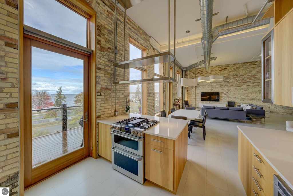 Modern kitchen with gas stove and sleek cabinetry, large windows showcasing bay views, and contemporary living area in a downtown Traverse City condo.