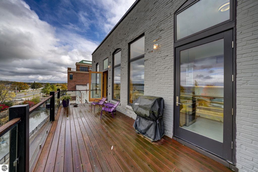 Modern downtown condo balcony with purple chairs, grill, and panoramic bay views in Traverse City, MI.