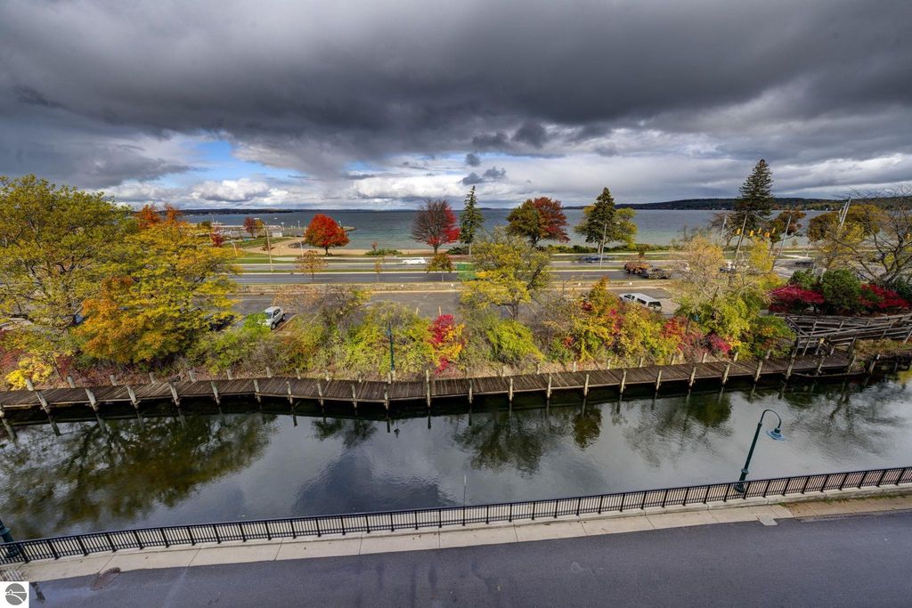 Scenic view from downtown condo at 237 E Front Street, Traverse City, featuring colorful autumn foliage, waterfront, and distant bay under a cloudy sky.