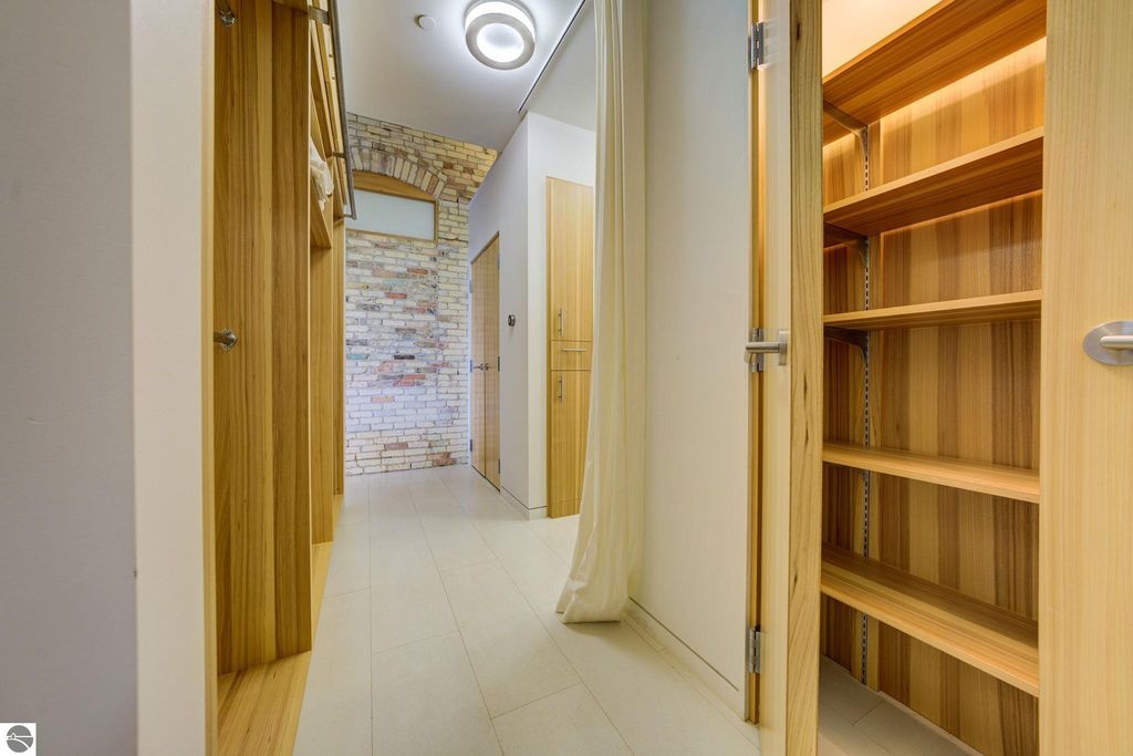 Modern interior hallway of a downtown condo, featuring wooden cabinetry, a brick accent wall, and ample natural light, highlighting the contemporary design and spacious layout.