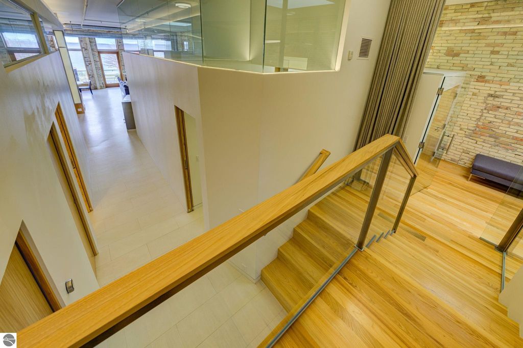 Modern interior view of a downtown condo at 237 E Front Street, showcasing open layout, wooden staircase, and large windows with natural light.