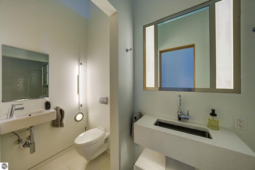 Modern bathroom with sleek fixtures, minimalist design, large mirror, and stylish lighting, showcasing a contemporary aesthetic ideal for the downtown condo at 237 E Front Street, Traverse City.