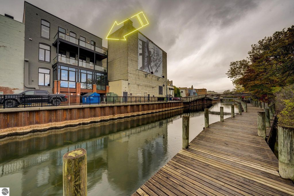 Modern downtown condo at 237 E Front Street, Traverse City, featuring large windows, balconies, and waterfront views along the canal, with a contemporary architectural design.