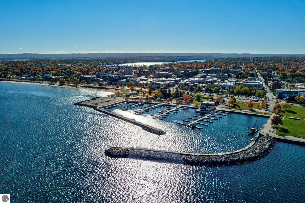 Aerial view of Traverse City, Michigan, showcasing downtown, waterfront, marina, and vibrant fall foliage along the bay.