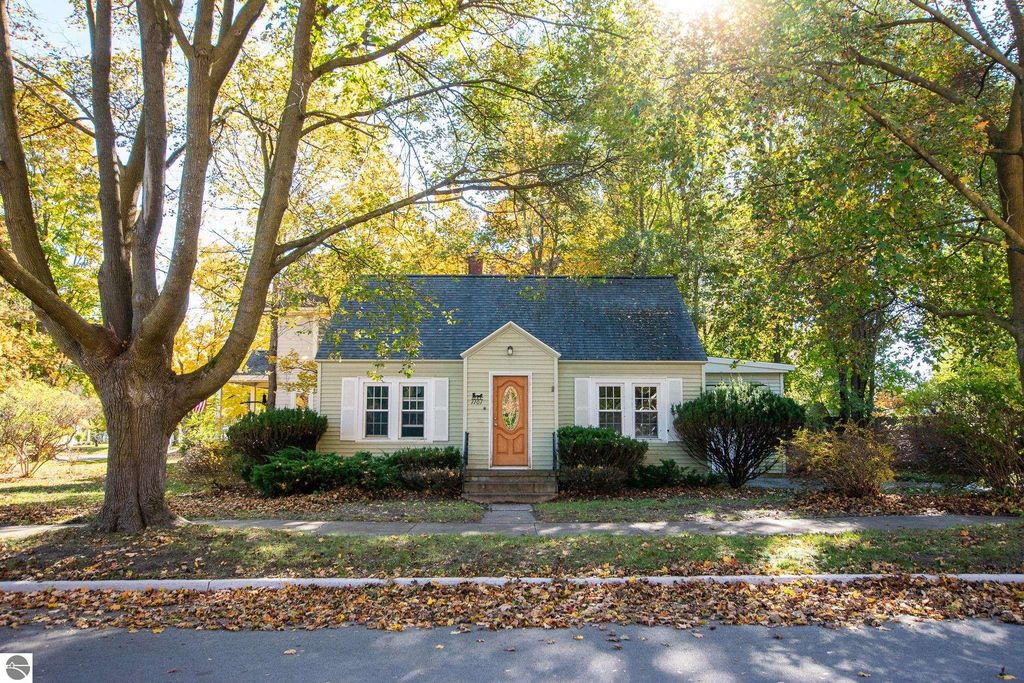 Charming 2-bedroom ranch home at 1101 Jefferson Avenue, Traverse City, surrounded by autumn foliage and landscaped yard, showcasing potential for renovation or new construction on a spacious lot.