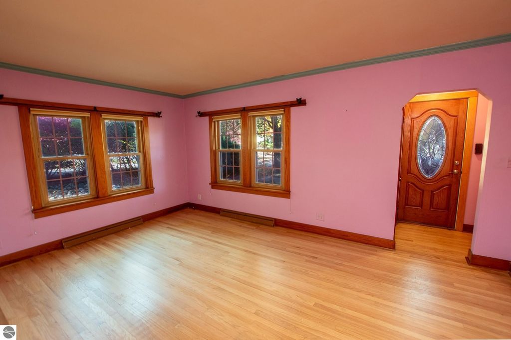 Interior view of a 2-bedroom ranch home at 1101 Jefferson Avenue, featuring pink walls, hardwood flooring, and large windows, highlighting natural light and potential for renovation or customization.