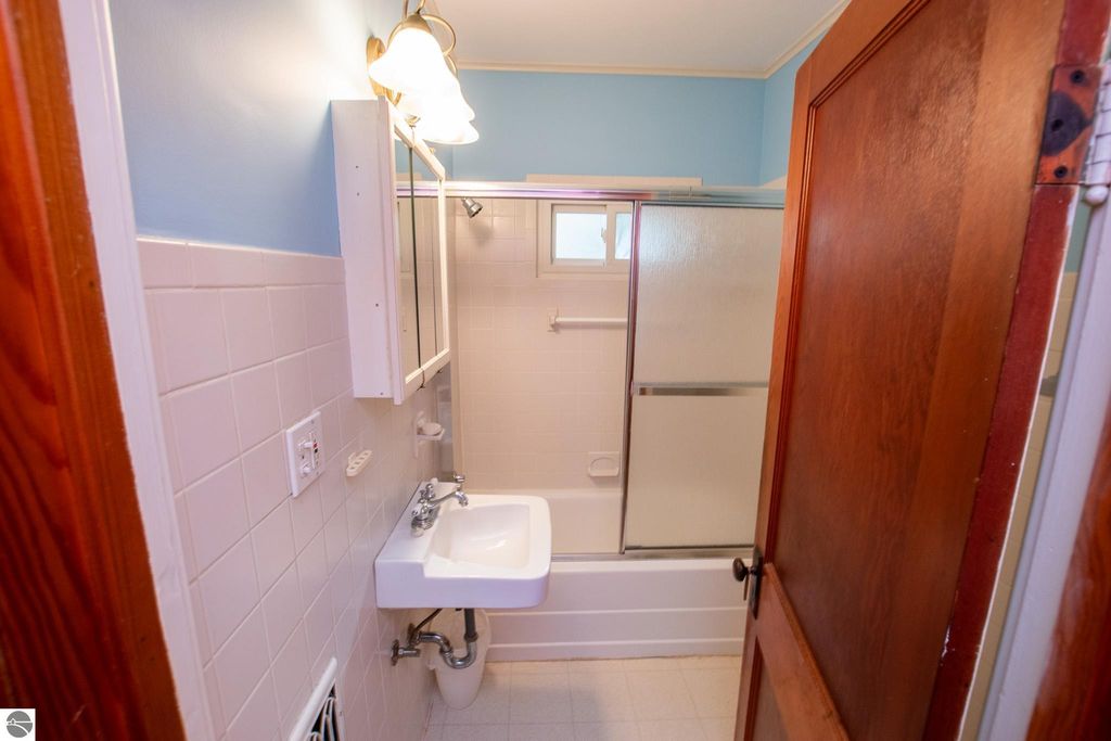 Bathroom interior featuring a sink, shower, and light fixture, showcasing a clean and functional design, relevant to the listing of a 2-bedroom home at 1101 Jefferson Avenue, Traverse City, MI.