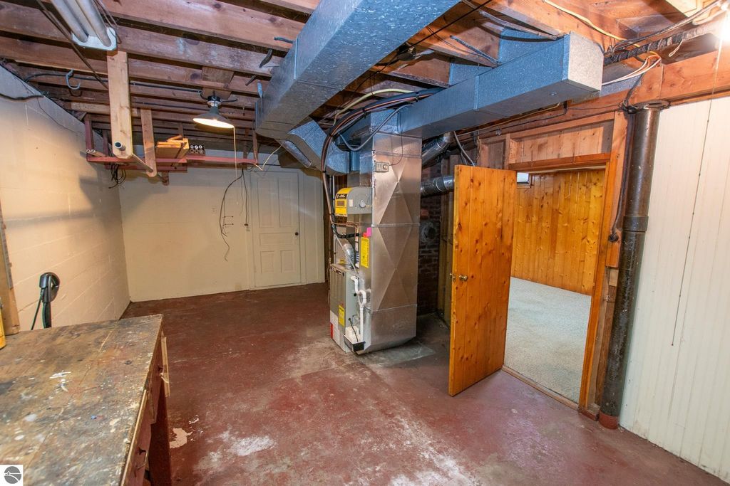Basement interior of 1101 Jefferson Avenue, featuring exposed beams, a furnace, and a door leading to another room, highlighting potential for renovation or additional use.