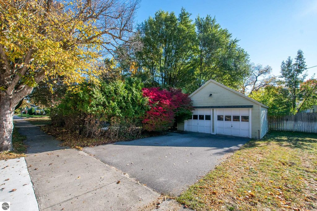 Oversized lot at 1101 Jefferson Avenue, Traverse City, featuring a two-car garage surrounded by vibrant fall foliage and landscaped yard, highlighting potential for renovation or new construction.