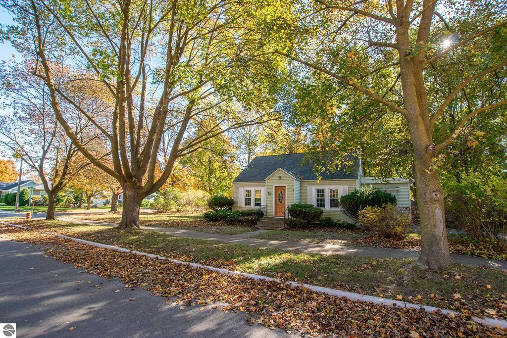 Charming 2-bedroom ranch home at 1101 Jefferson Avenue, surrounded by colorful autumn foliage and mature trees, showcasing potential for renovation or new construction in Traverse City's Slabtown neighborhood.