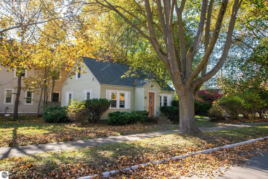 Charming 2-bedroom ranch home at 1101 Jefferson Avenue, surrounded by autumn foliage, showcasing a spacious front yard and steps leading to the entrance, ideal for renovation or new construction in Traverse City's Slabtown neighborhood.
