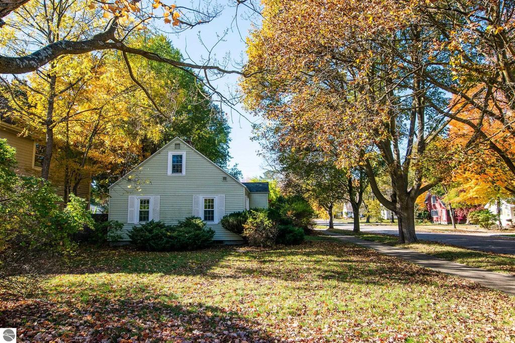 Charming 2-bedroom ranch home surrounded by colorful autumn foliage on Jefferson Avenue, Traverse City, showcasing potential for renovation or new construction on a spacious lot.